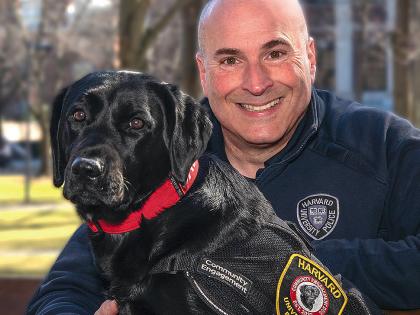 Harvard police officer Steven Fumicello poses with black Labrador retriever Sasha. 