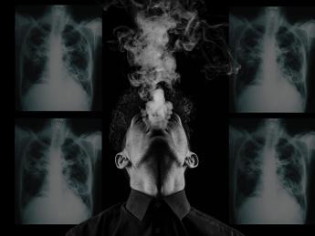 a person smoking in the foreground with x-rays of tuberculosis in the background