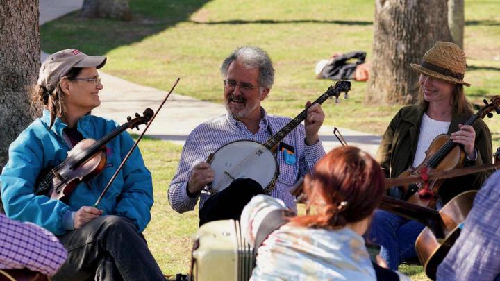 Two fiddlers and a banjo player take a break during an outdoor performance.