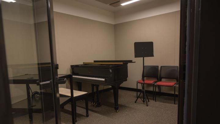 A music practice room with a piano and music stand