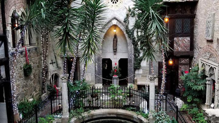 Photo of the cloister courtyard decorated for the holidays with strings of lights and touches of red amid the greenery